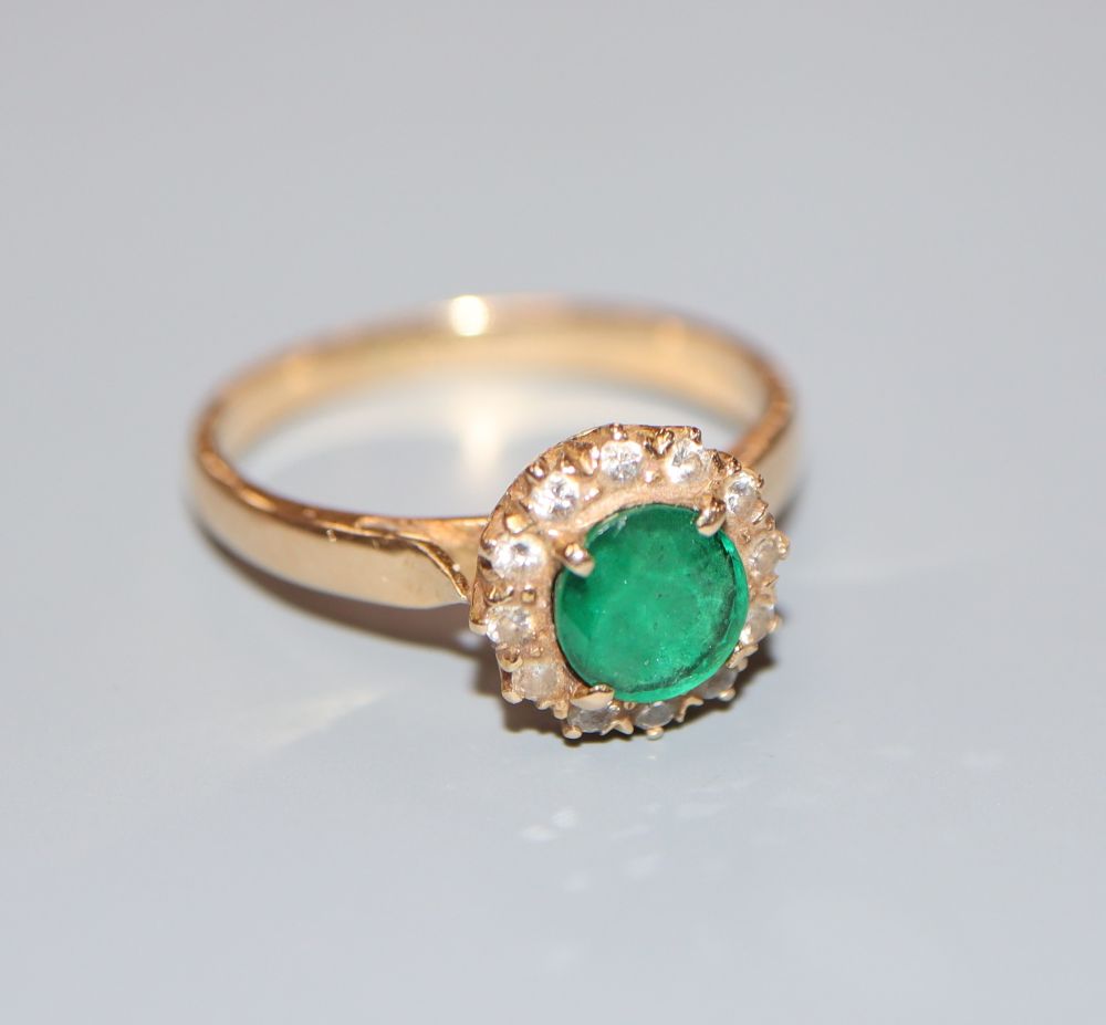 A yellow metal, emerald and diamond circular cluster ring, size L/M, gross 3.1 grams.